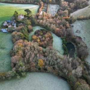 Arial shot of the ground of Trevina House including lots of woodland and a pond. The fields are frosty.