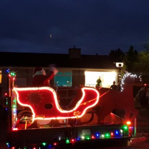 Photo of Liskeard Scouts Santa on his lit up sleigh waving to people in houses as he drives past on his tour of the town