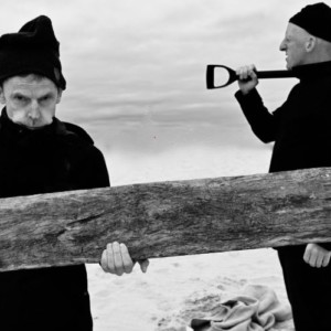 black and white photograph of one man holding a plank of wood and another man holding a spade